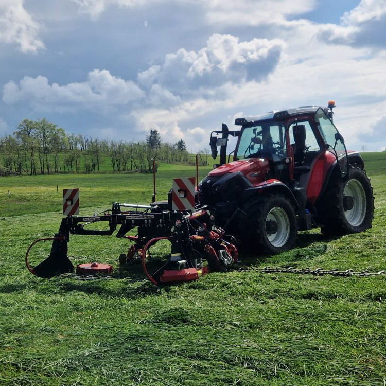 Traktor auf einer Wiese mit einem Anbaugerät